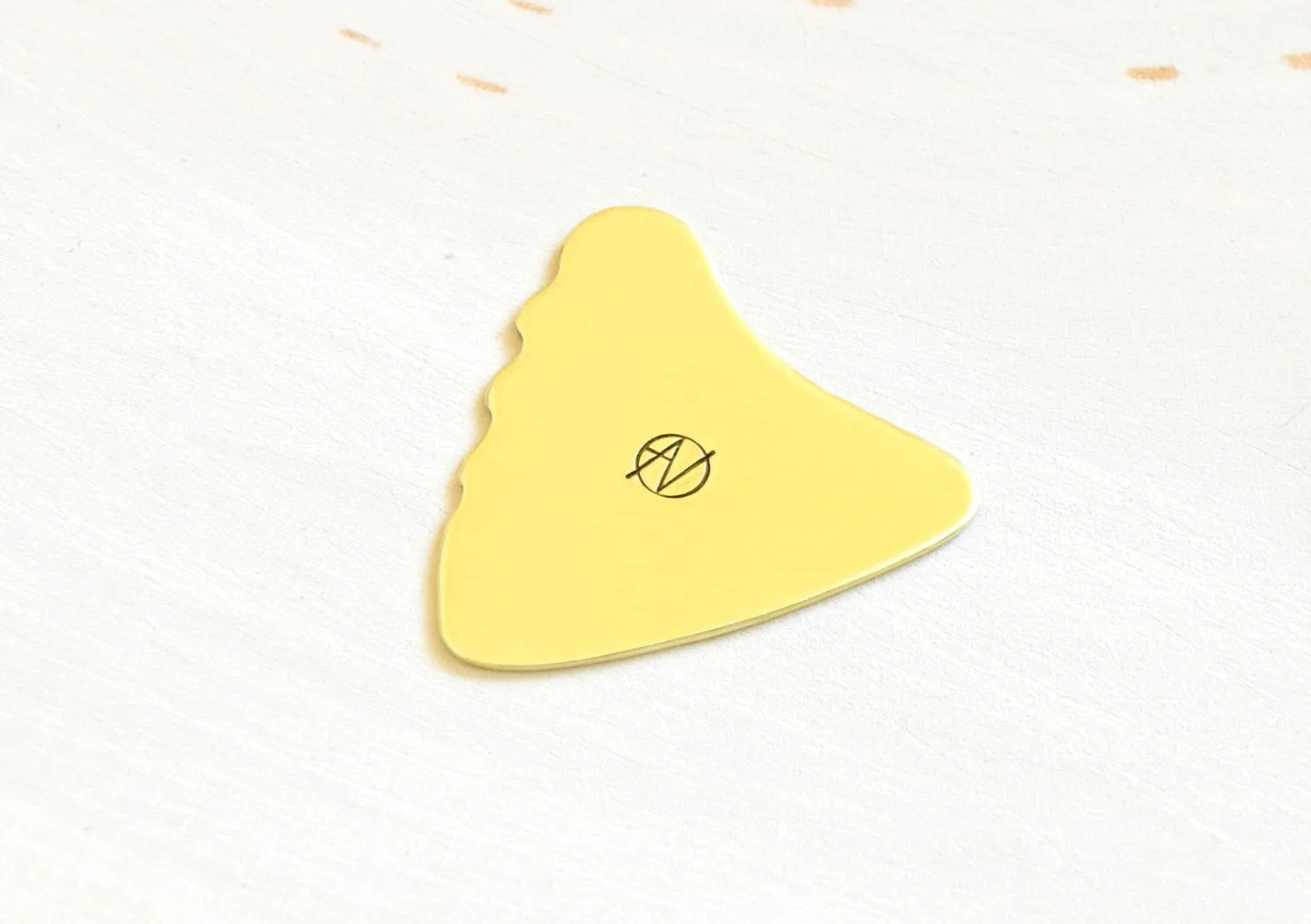 Shark Fin Brass Guitar Pick with a simple guitar theme